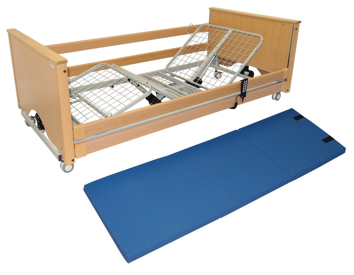 A picture of a crash mat, which has been unfolded and is on the floor alongside a bed frame.